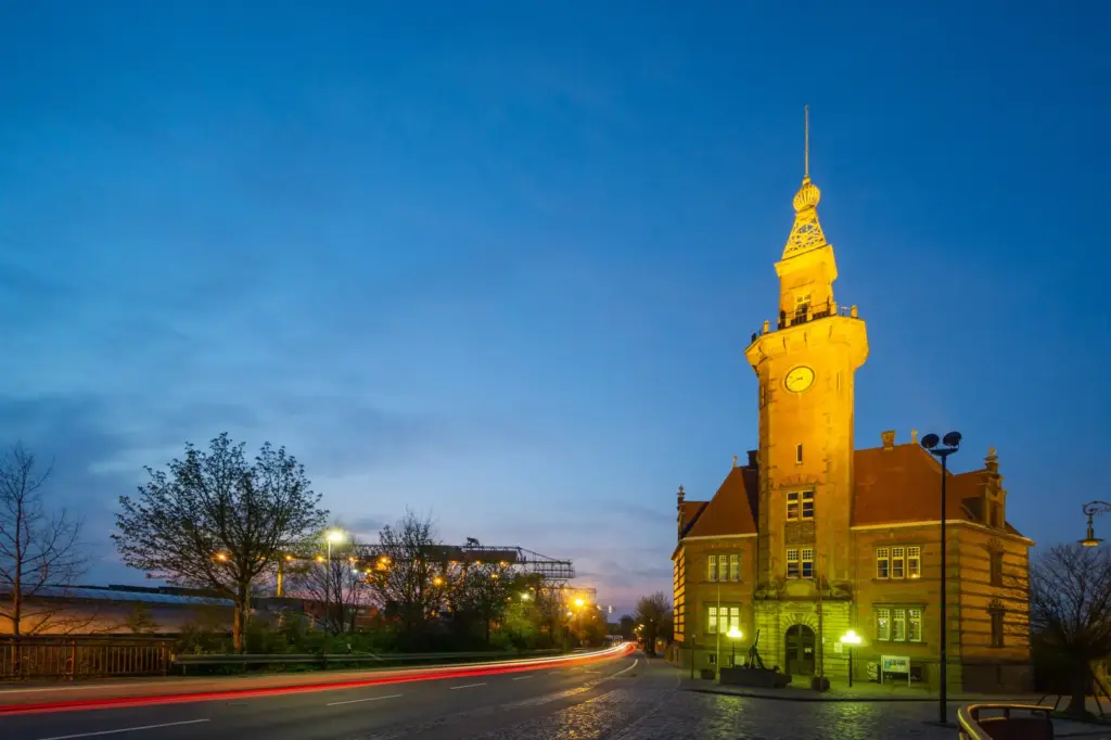 Altes Hafenamt Dortmund mit beleuchtetem Uhrturm in der Abendd&auml;mmerung.