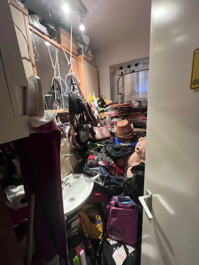 Zugestelltes Badezimmer mit Waschbecken unter gestapeltem Hausrat.