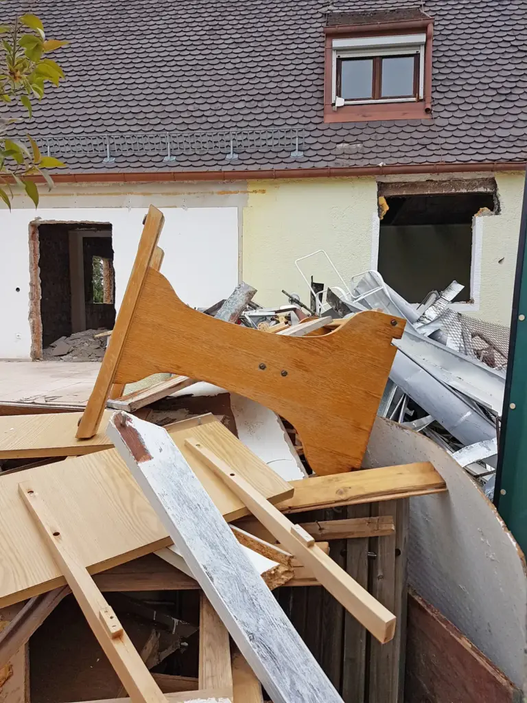 Bauschutt und alte M&ouml;belteile vor einem entkernten Wohnhaus.
