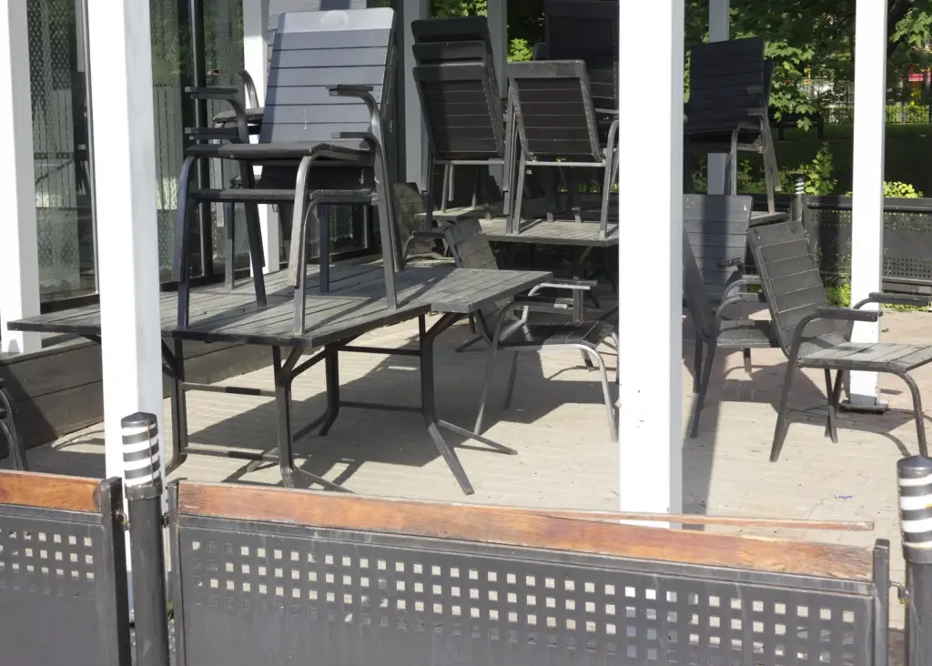 Gestapelte St&uuml;hle und Tische auf der Terrasse eines geschlossenen Caf&eacute;s.