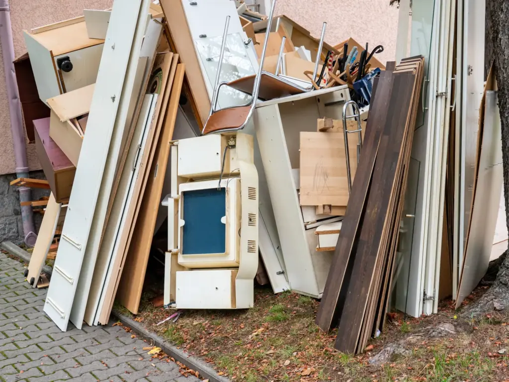 Zerlegte Schrankteile und Bretter lehnen an einer Hauswand.